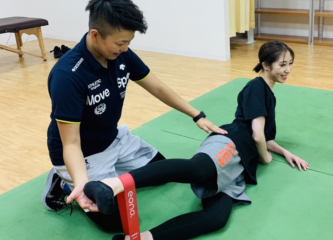 バランスボールに乗る利用者と指導するトレーナー